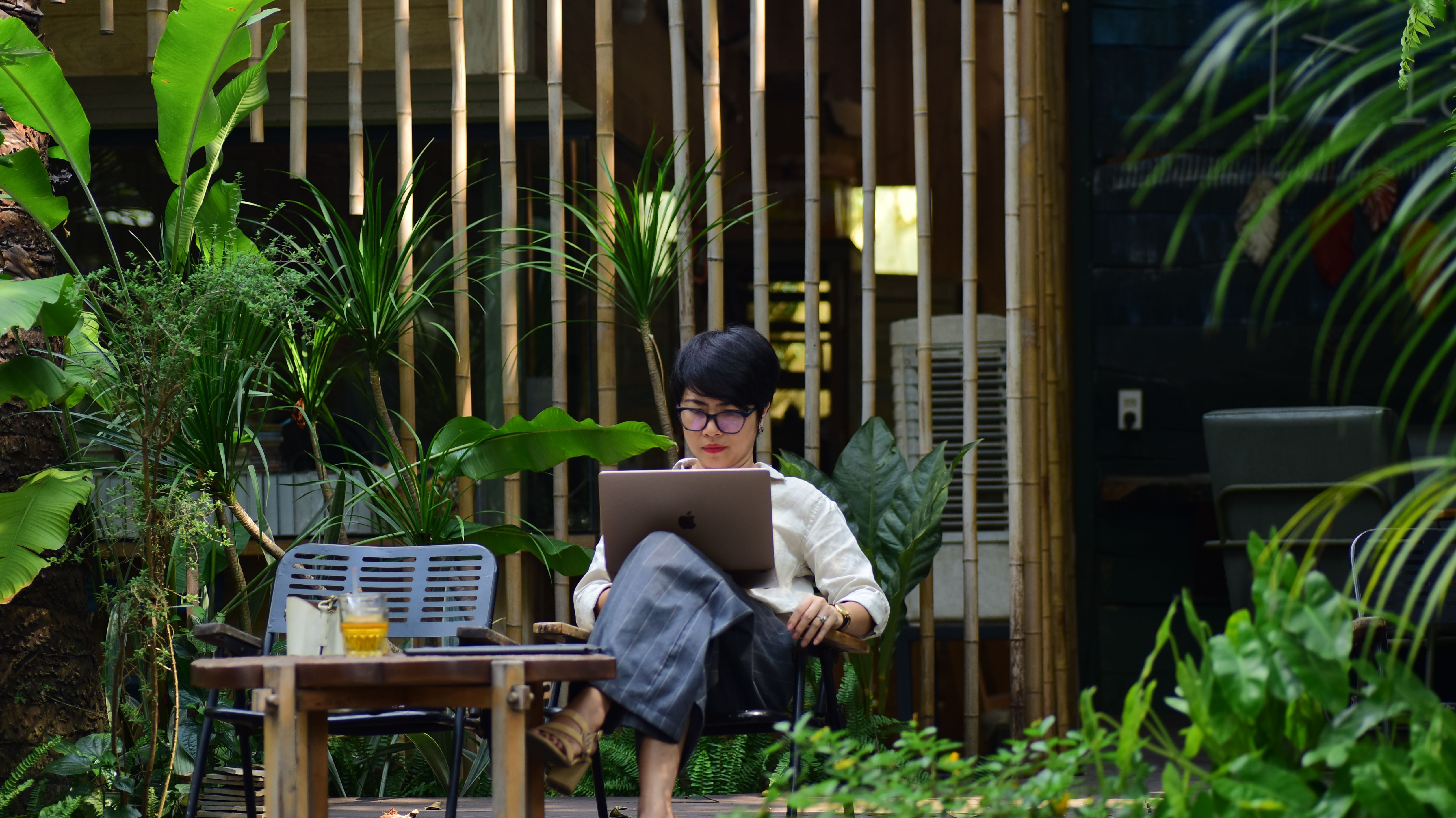 Remote worker using a laptop in a leafy garden workspace.